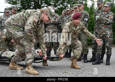 Us-Armee Sgt. 1. Klasse Sherrie Porter, vorne links, um kombinierte Waffen Training Center (CATC), 7th Army Training Befehl und die U.S. Army Staff Sgt zugeordnet. Stephen Pyon, Vordergrund rechts, 1 Geschwader zugewiesen, 91st Cavalry Regiment, 173Rd Airborne Brigade die Verwendung einer falten wurf während ein CATC bekämpfen Lebensretter Kurs auf Rose Barracks, Vilseck, Deutschland, 13. Juni 2018 zeigen. Dieser Kurs vermittelt die unmittelbare, weit nach vorn medizinische Versorgung auf einem weit verstreuten Schlachtfeld während Weitere medizinische Behandlung und Evakuierung wartet. Stockfoto