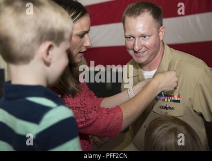 NORFOLK, Virginia (12. Juni 2018) - - Senior Chief Aviation Elektroniker Phillip Sawicki, von den Niagara Falls, New York, zu USS Gerald R. Ford's (CVN 78) Aviation intermediate Instandhaltungsabteilung belegt, ist zu seiner aktuellen Rang durch seine Familie während eines Senior Chief Petty Officer pinning Zeremonie in den Hangar bay festgesteckt. Ford hatte 14 Chief Petty Officers in den Rang eines Senior Chief Petty Officer. Stockfoto