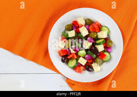 Leckere griechische Salat mit frischem Gemüse, Schafskäse grün und Kalamata Oliven, rote Zwiebel Zwiebeln auf weißen Teller am Tisch matte, leicht und gesund reci Stockfoto