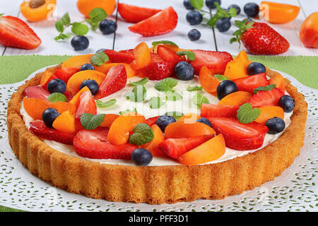 Leckere hausgemachte cremigen Mascarpone Käsekuchen mit frischen Erdbeeren, Aprikosen und Heidelbeeren auf Papier Serviette auf weißen Tisch mit Früchten eine Stockfoto