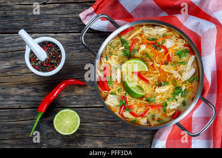 Lecker und würzig Thai Chicken Green Curry Nudelsuppe in Kochtopf auf alten, dunklen Holztisch mit Küchentuch, traditionelle klassische Rezeptur-, Sicht Stockfoto