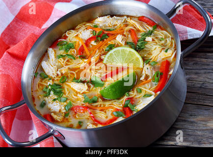 Lecker und würzig Thai Chicken Green Nudelsuppe curry mit Kokosmilch in Kochtopf auf alten, dunklen Holztisch mit Küchentuch, traditionelle Cla Stockfoto