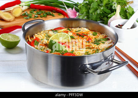 Spicy Thai Chicken Curry und Gunst grüne dicke Nudel Suppe mit Kokosmilch, Gemüse und Kräuter in den Kochtopf auf Holztisch mit Zutaten aus Stockfoto