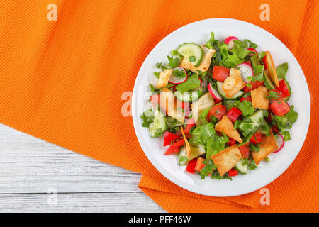 Köstliche traditionelle Fattoush pita Brot oder Salat mit Croutons, frischem Gemüse und Kräutern, auf weißem Schild auf Holztisch, einfache und gesunde Authen. Stockfoto