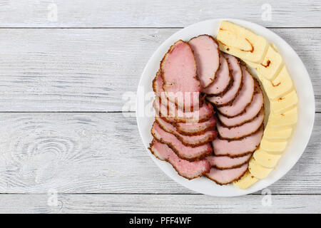 In Scheiben geschnittene Wurst und würzigem Mozzarella Käse auf dem Teller auf weißem Holz- Tabelle, Ansicht von oben Stockfoto