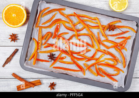Köstlich süßen Selbstgemachten kandierten Orangen und Zitrone Schalen gekocht auf Backblech mit Zimt, Muskat und Anis Sterne. Die Hälfte der Orange und Zitrone auf Holz Stockfoto