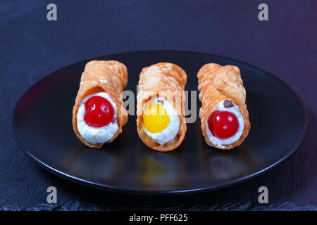 Köstliche hausgemachte sizilianische Cannoli - traditionelle italienische Dessert, Füllung mit Ricotta Käse auf schwarze Platte auf dunklem Schiefer Fach, authentische Klassische re Stockfoto