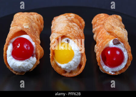 Köstliche hausgemachte sizilianische Cannoli füllen mit ricotta Käse und cocktailkirschen auf schwarze Platte auf dunklem Schiefer Fach, authentische klassisches Rezept, vie Stockfoto