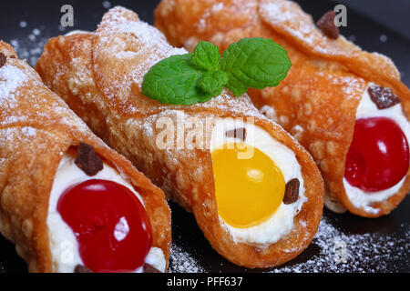 Köstliche hausgemachte sizilianische Cannoli - traditionelle italienische Dessert, Füllung mit Ricotta Käse auf schwarze Platte auf dunklem Schiefer Fach, authentische Klassische re Stockfoto