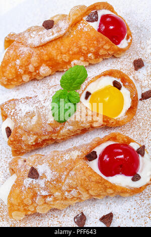 Leckere hausgemachte italienische Dessert - sizilianische Cannoli, Füllung mit Ricotta Käse Sahne und Kirschen auf weissem bestreut mit Schokolade Pulver, Stockfoto
