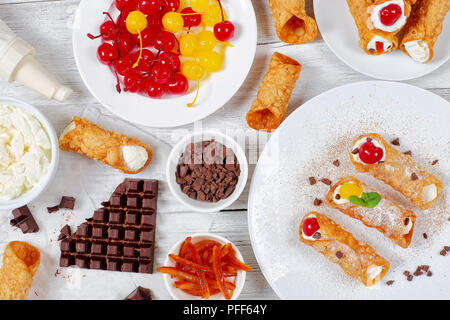 Sizilianische Cannoli oder Creme Hörner, ricotta Sahne und Kirschen auf weiße Platten mit Zutaten - Schokolade, Orangeat, Gebäckbeutel o Stockfoto