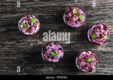 Sommer Nachtisch von schwarzen Johannisbeeren und gefrorene ricotta Yogurtmousse bestreut mit fein gehackte Schokolade mit Minze im Glas Tassen eingerichtet Stockfoto