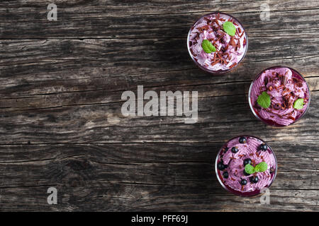 Sommer Nachtisch von schwarzen Johannisbeeren und gefrorene ricotta Joghurt Mousse bestreut mit fein gehackte Schokolade mit Minze im Glas Tassen eingerichtet Stockfoto