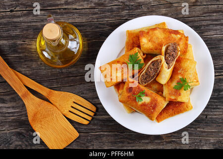 Hackfleisch und Leber Gefüllte Crepes Crisped in Olivenöl auf weiße Platte auf alten Holz- Tabelle, Ansicht von oben Stockfoto