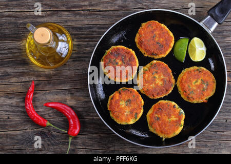 Köstliche frisch gebratenen Fisch, hausgemachte Kuchen mit Kartoffelpüree auf Skillet mit Kalk, Scheiben, auf dunklen Holztisch mit Flasche Olivenöl, klassische recip Stockfoto