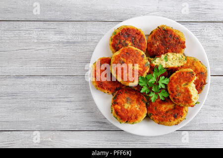 Köstliche frisch gebratenen Fisch, hausgemachte Kuchen mit Kartoffelpüree auf weiße Platte mit Petersilie auf alten Holztisch, klassisches Rezept, Ansicht von abov Stockfoto