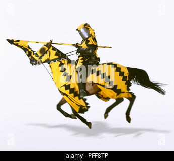 Ritter vor Laden auf dem Pferd mit spitzen Speer, Pferd, drapiert in uniform gelb und schwarzen Stoff passenden Ritter, Seitenansicht. Stockfoto