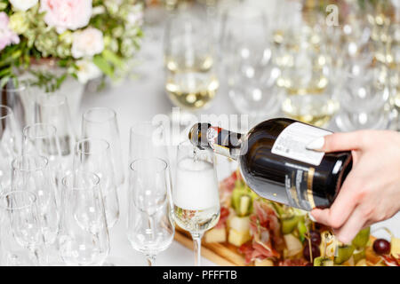 Barkeeper gießen Champagner oder Wein in die Gläser auf dem Tisch im Restaurant. feierliche Hochzeit oder ein frohes neues Jahr und Veranstaltungsräume Stockfoto