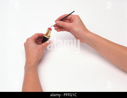 Hände, die Lippenstift und Make-up-Pinsel Stockfoto