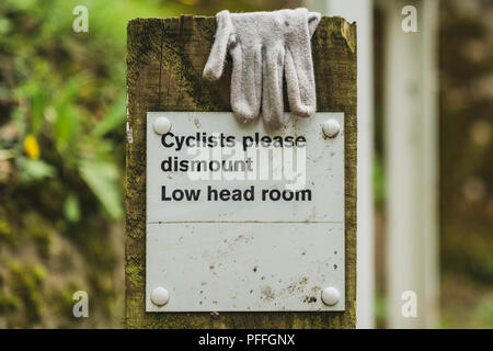 Zeichen: Radfahrer bitte, niedrigen Raum abbauen - mit einem Handschuh, Llangollen Canal in der Nähe von Ellesmere, Shropshire, England, UK gesehen Stockfoto