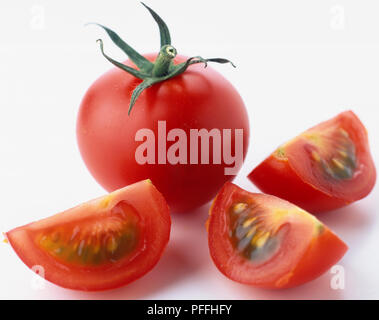 Ganze Tomaten mit Stiel, und in Scheiben geschnittene Tomaten mit fleischigen Fruchtfleisch und Samen. Stockfoto