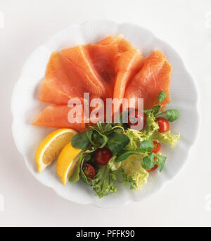 Geräucherter Lachs mit Salat und Keile von Zitrone, auf einer Platte Stockfoto