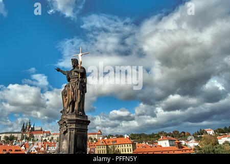 Statue von Johannes dem Täufer auf der Karlsbrücke und der Prager Burg entfernt. Stockfoto