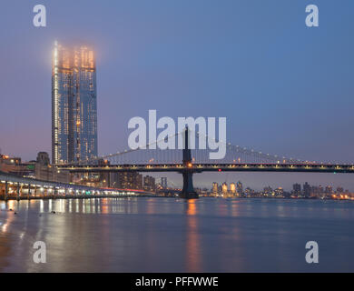 Die Manhattan Bridge an einem nebligen Abend; sie suchen den East River mit der Williamsburg Bridge im Hintergrund. Stockfoto