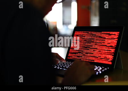 Computer Hacker Silhouette der Eingabe am Computer in einen dunklen Raum. Arbeiten an der binäre Code Technologie. binäre Daten, Computerkriminalität und Netzwerksicherheit. Stockfoto