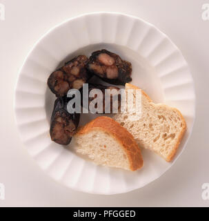 Scheiben von Morcilla (Blutwurst), spanische Würstchen serviert mit Brot auf den Teller, Ansicht von oben Stockfoto