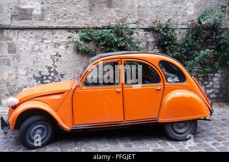 Frankreich, eine orange Citroen 2CV in einer gepflasterten Straße geparkt Stockfoto