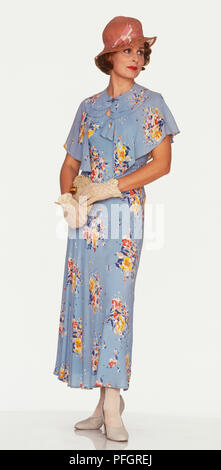 Eine Frau trägt ein 1930er Jahre blaues Kleid mit einem floralen Designs Stockfoto