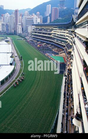 China, Hongkong, Happy Valley Pferderennbahn, Menschenmassen in den Ständen entlang der Rennstrecke, Blick auf die Pferderennbahn suchen Stockfoto