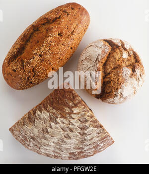 Rustikales Brot, einschließlich dreieckigen Stück Roggenbrot (hausbrot), Runde, knusprige Laib Vollkornbrot (Vollkorn-Bauernbrot) und Laib multi-Korn Brot (Siebenkornbrot) bestreut mit Sesam, von oben betrachten Stockfoto