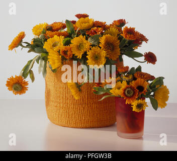 Orange und Gelb Tagetes in großen Korb und kleines Glas Vase Stockfoto
