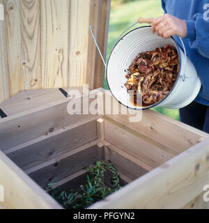 Trinkgeld organische Abfälle aus Metall Eimer in Holz- komposttonne, close-up Stockfoto