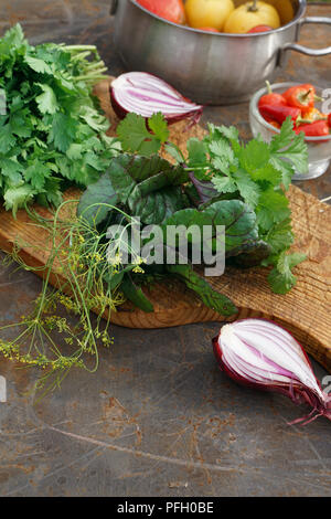 Frische Petersilie, Dill, Mangold, Koriander auf Holzbrett und Tomaten und Chile auf Eisen backgrownd. Im rustikalen Stil. Stockfoto