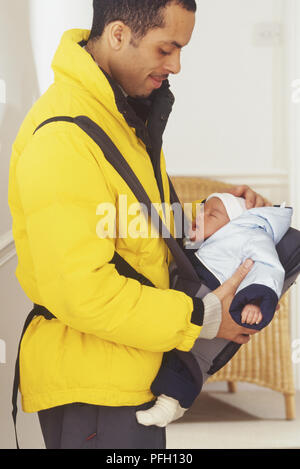 Mann hält Schlafen Baby Mädchen in Babytragetuch, eine Hand auf den Kopf Stockfoto