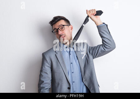 Ein Porträt von einem besorgten junge Unternehmer einen Riegel, als ob selbst auflegen. Ein Studio gedreht. Stockfoto