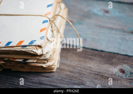 Stapel alte Briefe in Umschläge, mit Gewinde gebunden, auf einem Holztisch Stockfoto