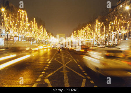 Frankreich, Paris, Champs Elysees mit Blick auf den Arc de Triomphe, mit Bäumen boardering der Straße durch Lämpchen beleuchtet. Stockfoto