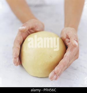 Mehl Hände halten einen glatten Ball von Teig Stockfoto