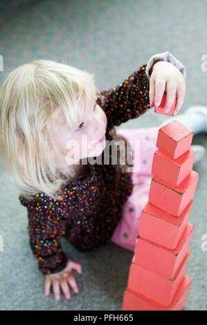 Mädchen stapeln rot Holzklötze in der Größe bestellen Stockfoto