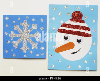 Zwei Weihnachtskarten, mit Silber Glitzer Schneeflocken und Sterne und das Gesicht des einen Schneemann eingerichtet Stockfoto