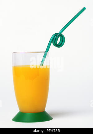Grünen Trinkhalm in Schleife in einem Glas Orangensaft verdreht Stockfoto