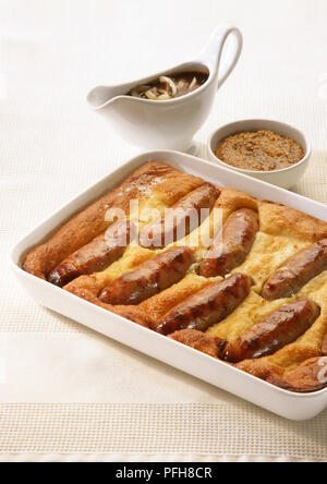 Kröte in der Bohrung, Würstchen im Teig gebacken, serviert mit Zwiebel Sauce und Senf, close-up Stockfoto