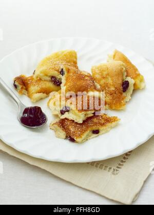 Kaiserschmarrn, ein traditionelles österreichisches Pfannkuchen mit Rosinen, auf Platte mit pflaumenmus auf Löffel serviert, close-up Stockfoto