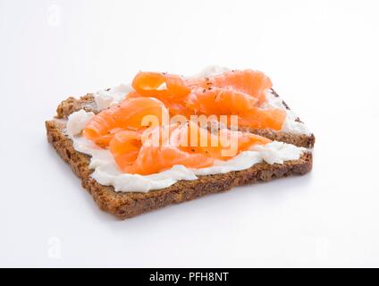 Sandwich offen, mit Lachs, Frischkäse und schwarzer Pfeffer auf Pumpernickel Bread, close-up Stockfoto