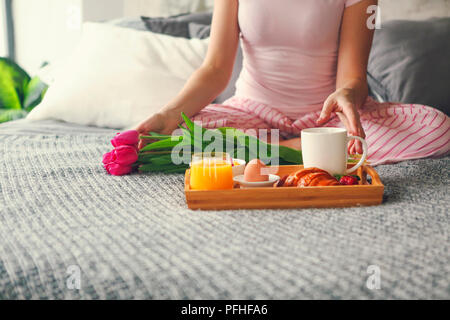 Junge Frau mit Frühstück im Bett. Lifestyle Konzept Stockfoto