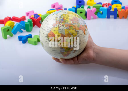 Kleines Modell gobe in Hand mit bunten Buchstaben hinter Stockfoto